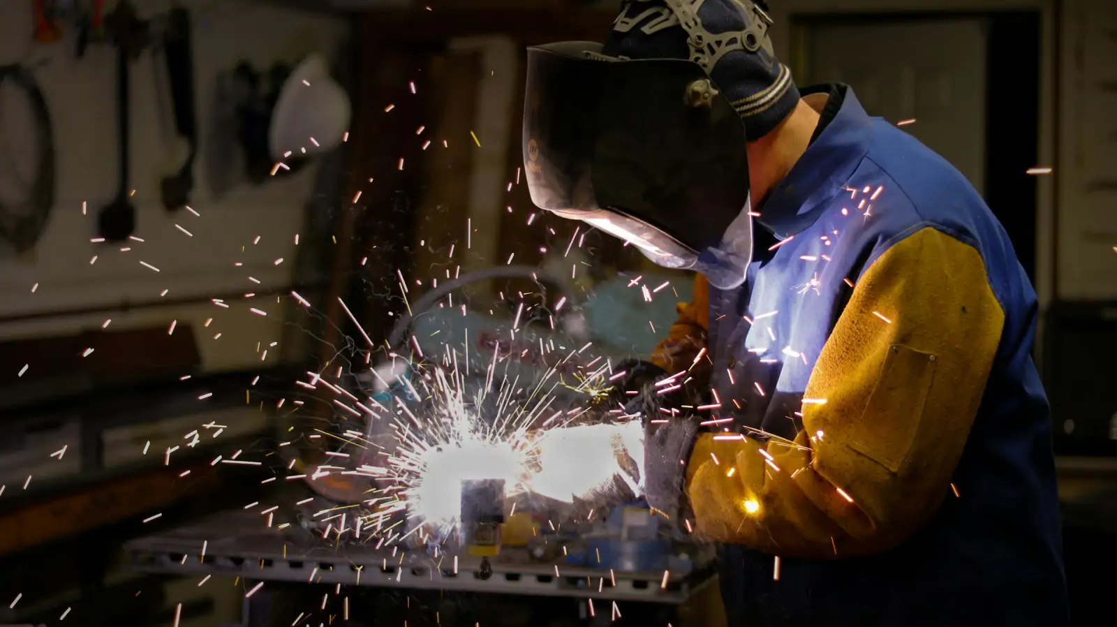 Fabricator welding a steel frame with sparks in a workshop